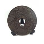 A LARGE CHINESE HARDSTONE BI DISC carved with calligraphy and stylised dragons, 12 ins diameter.