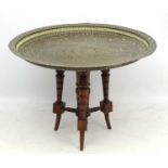 An early 20thC Indian brass topped circular table with pierced top on an associated English walnut
