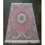 Carpet / rug : a Chinese pink ground rug having green, red , white and sage green colours,