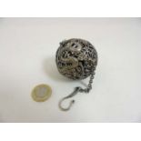 A Chinese white metal pomander of spherical form, decorated with four clawed dragon,