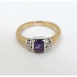 A 9ct gold ring set with central amethyst flanked by diamonds.
