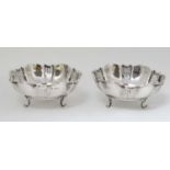 A pair of silver bowls with scrolled feet and pierced decoration.