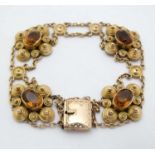 A 9ct gold and gilt metal bracelet set with 5 ciritine stones set within scrolling mounts