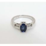 An 18ct white gold ring set with oval blue stone flanked by diamonds.
