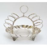 A silver plate 6-slice toast rack with integral glass butter dish to centre.