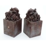 A pair of Chinese red soapstone bookends? surmounted by a dog with three puppies.