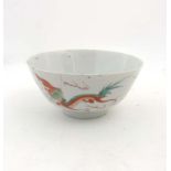 An oriental hand painted ceramic bowl depicting firebirds and dragons in reds, greens and yellows.
