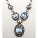 A silver necklace set with 5 oval topaz coloured blue stones bordered by marcasite. Approx.