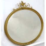 A c.1900 gilt oval bevelled wall mirror with urn and acanthus swag style decoration.
