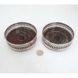 A pair of silver plated bottle coasters with turned bases.