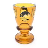 A Bohemian amber glass vase of goblet form with black and clear glass cut decoration depicting