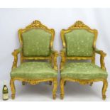 A pair of early 20thC gilt Italian open arm chairs standing on swept legs with carved toes and