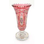 A cranberry and clear glass vase with hand painted floral decoration and gilt scrolling detail.