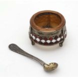 A gilt and enamel decorated base metal salt with glass liner together with salt spoon.
