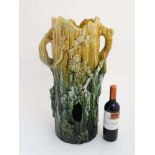 A c1900 Majolica stick stand formed as a tree stump with trailing flora in shades of yellow and
