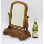 A Victorian walnut oval toilet mirror on cupids bow base.