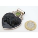 A silver pendant of heart form set with engraved dark green hardstone depicting a cat,