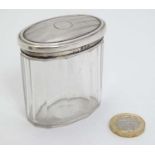 A glass dressing table pot with silver lid.