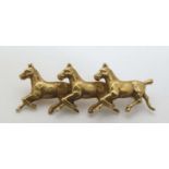 A 14ct gold brooch with trio of running horse decoration.