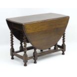 An early 20thC oak oval Gate leg Table with barley twist legs and squared stretchers.