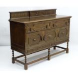 An early / mid 20thC oak side board with geometric moulding throughout and standing on barley twist