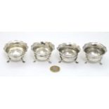 A set of 4 silver salts each with three legs and flared rims.