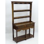 An early 20thC oak Dresser of small proportions with two tier plate rack having a shaped frieze and