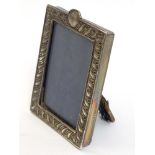 A Victorian silver photograph frame with embossed decoration.