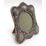 A silver photograph frame with embossed cherub, C-scroll and floral decoration etc.