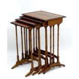 An early 20thC mahogany nest of four tables with inlay and applied beading to the top,