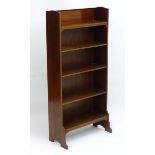 An early 20thC Sheraton Revival freestanding five shelf bookcase with raised inlaid back stand and