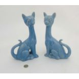 A pair of 20th C comical cats stylized as Siamese, decorated in a light blue glaze with a red eye,