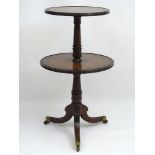 A Regency Mahogany two tier Dumb Waiter with a ring turned tapering column and standing on three