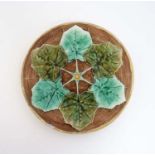 A 20th C majolica plate with 6 green leaf decoration,