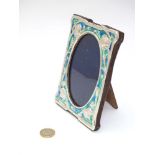 A 21stC Art Nouveau style silver photograph frame with embossed floral decoration and enamel detail.