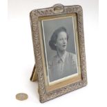 A silver photograph frame with embossed decoration.