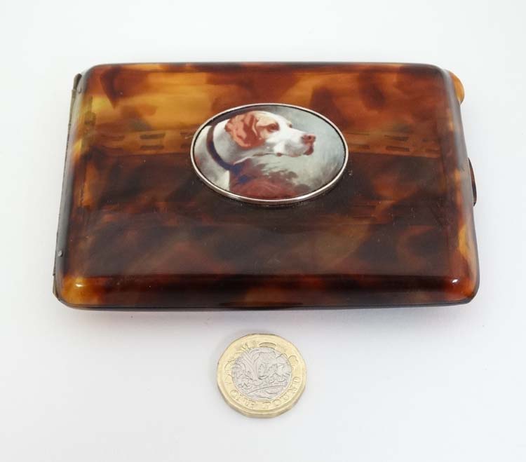 A faux tortoiseshell cigarette case with later applied ceramic decoration depicting dog head,