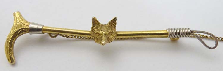 A 9ct gold stock pin / brooch formed as a riding crop / whip with fox head decoration to centre.