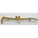 A 9ct gold stock pin / brooch formed as a riding crop / whip with fox head decoration to centre.