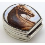 A silver pill box formed as a horseshoe with horse head decoration to top.