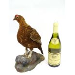 Taxidermy: A mount of a red grouse, posed standing, affixed to a rock plinth,