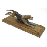 A desk top letter clip formed as a cold painted bronze hound / dog mounted on an stained oak base.