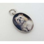 A silver fob with later applied ceramic cabochon with dog decoration.