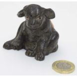 An early 20thC novelty cast metal pin cushion formed as a seated puppy dog with glass eyes.