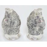 A novelty white metal salt and pepper cruet formed as board heads with red stone eyes. marked .800.