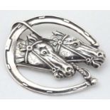 A silver brooch formed as a horseshoe with riding crop / whip and horse head decoration.