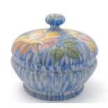 A hand painted lidded glass powder bowl decorated in polychrome with roses and foliage on a blue