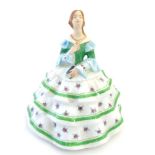A New Chelsea figurine depicting a female wearing a tiered dress with rose sprigs and green borders.