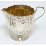 A Victorian silver pedestal cream jug with fluted and acanthus decoration and gilded interior.