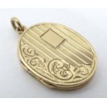 A 9ct gold locket of oval form hanging engraved acanthus and engine turned decoration.